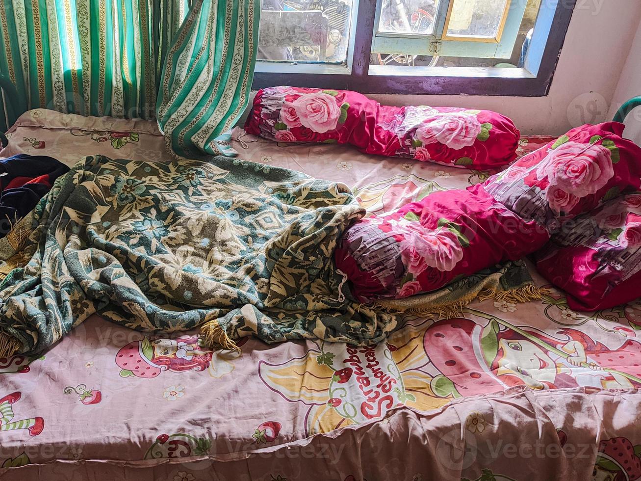 The bedroom is a mess. A child's room with a messy bed and pillows, bolsters and quilts that have not been tidied up. real life. photo