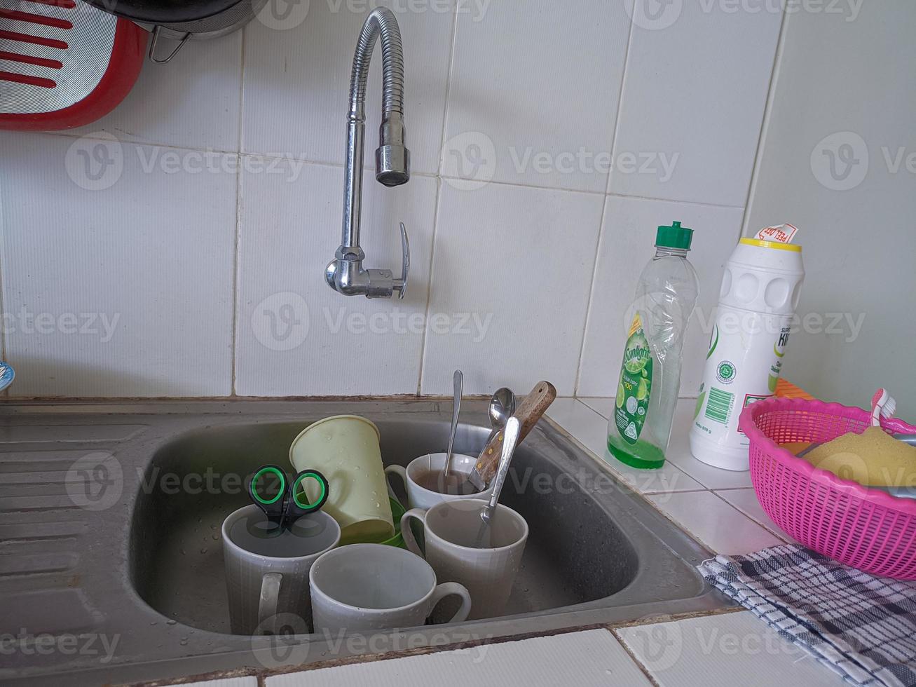 Dirty dishes and glasses in the sink that have not been washed. Piles of dirty dishes and glasses that haven't been washed, real life at the end of the year photo