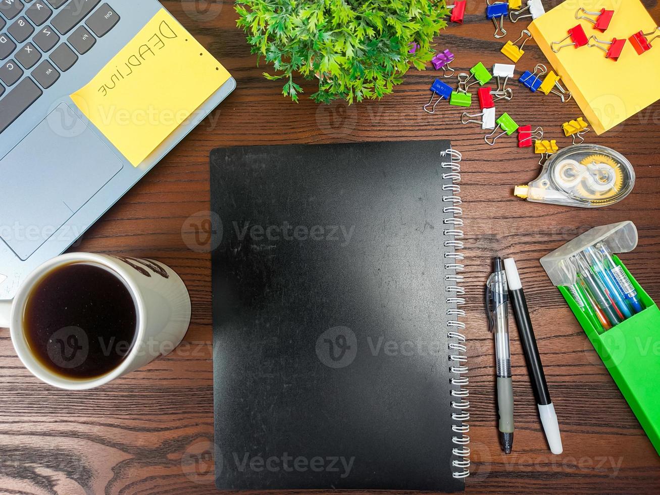 Flat lay, black book mock up. workspace in the background of the office desk from the top view. with black books, laptops, office supplies, pencils, green leaves, and coffee cups in the wooden table. photo