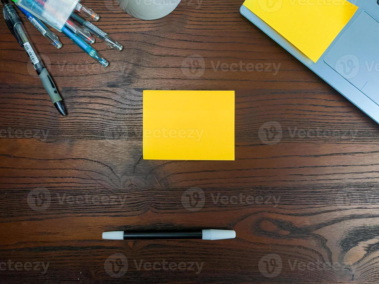 Flat lay, mock up yellow notes. workspace in the background of the office desk from the top view. with yellow notes, laptops, office supplies, pencils, and coffee cups in the wooden table. photo