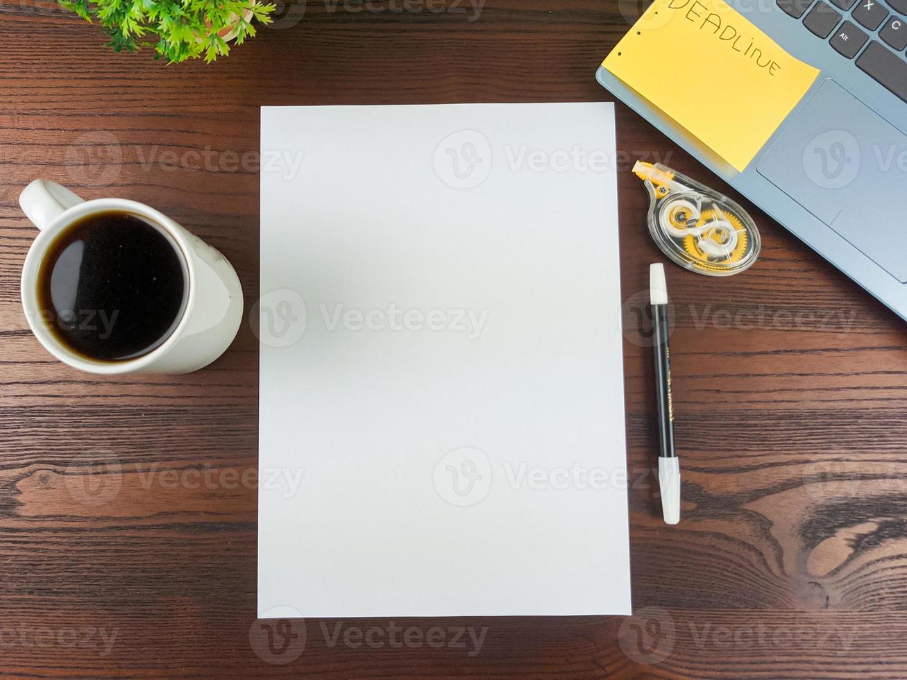 endecha plana, papel simulado. espacio de trabajo en el fondo del escritorio de la oficina desde la vista superior. con papel blanco en blanco, computadoras portátiles, útiles de oficina, lápices, hojas verdes y tazas de café en una mesa de madera. foto