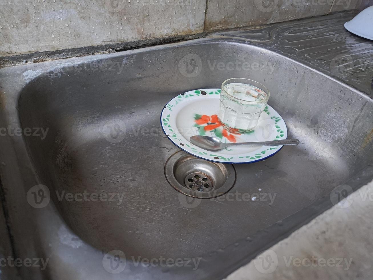 platos y vasos sucios en el fregadero que no han sido lavados. montones de platos sucios y vasos que no han sido lavados, la vida real al final del año foto