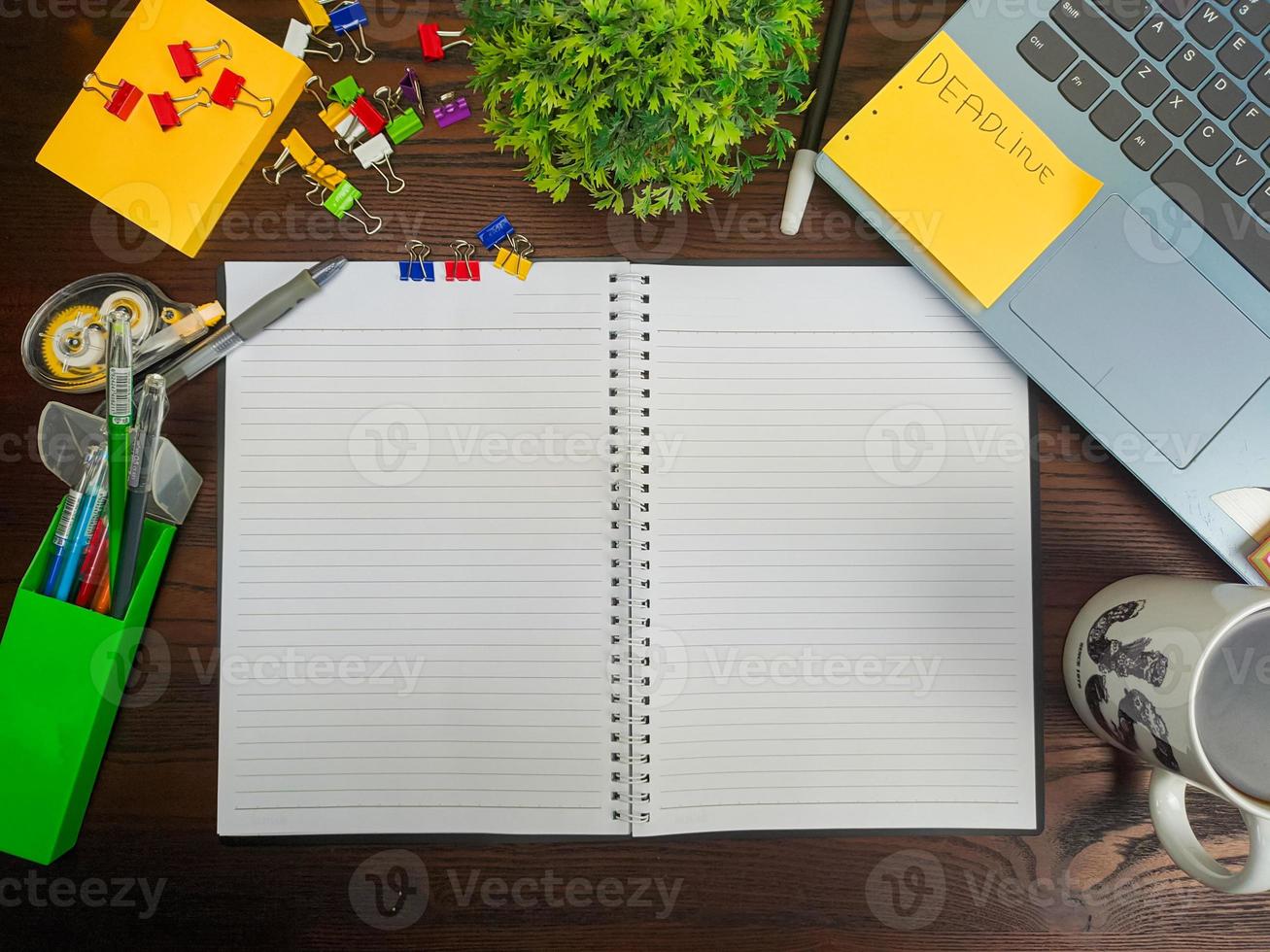 endecha plana, una maqueta de un cuaderno. espacio de trabajo en el fondo del escritorio de la oficina desde la vista superior. con cuadernos blancos, portátiles, útiles de oficina, lápices y tazas de café en el escritorio de madera. foto
