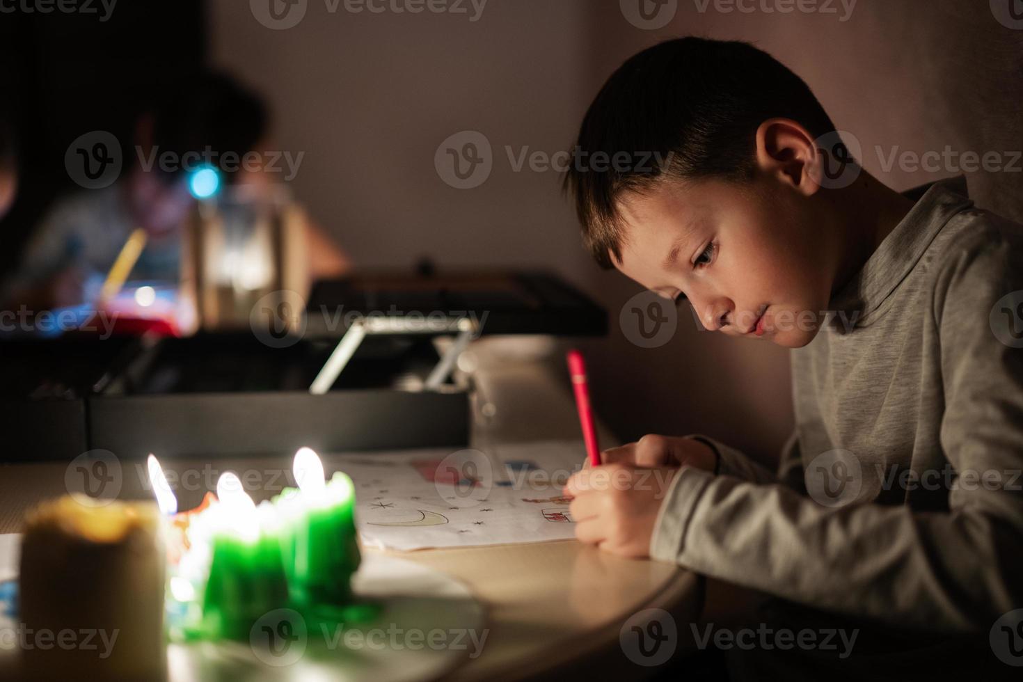 Family spending time together during an energy crisis in Europe causing blackouts. Kids drawing in blackout. photo