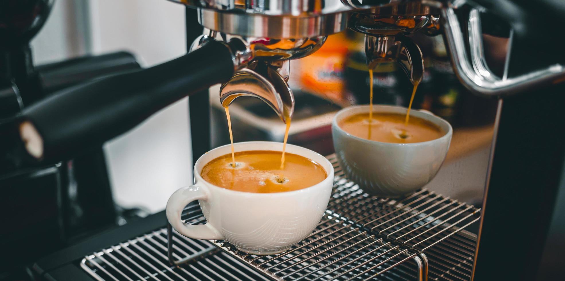 extracción de café de la máquina de café con un portafiltro que vierte café en una taza, espresso de la máquina de café en la cafetería foto