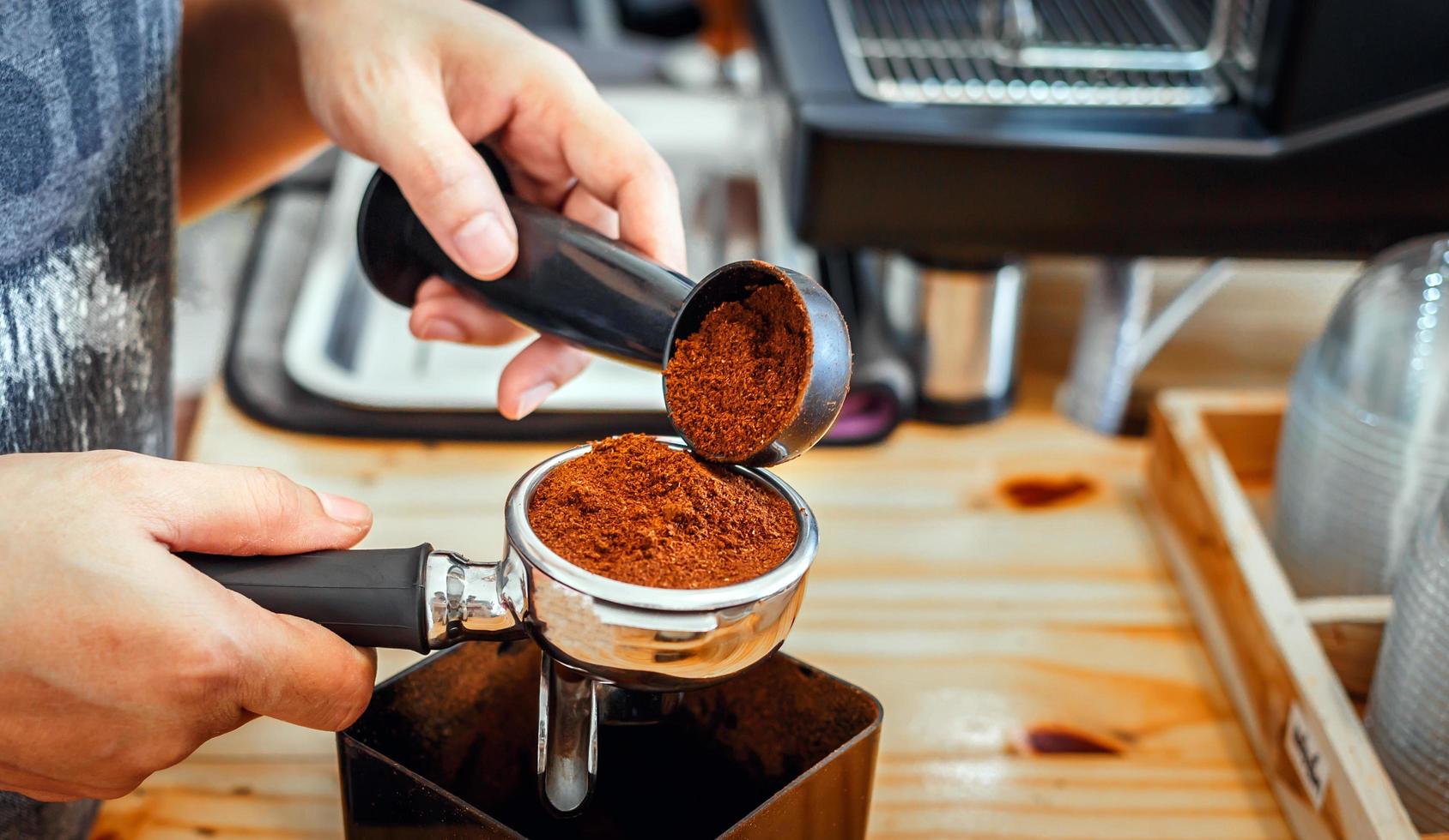 Barista pours coffee bean roaster powder ground coffee pouring into a portafilter with a barista hand at the coffee shop photo