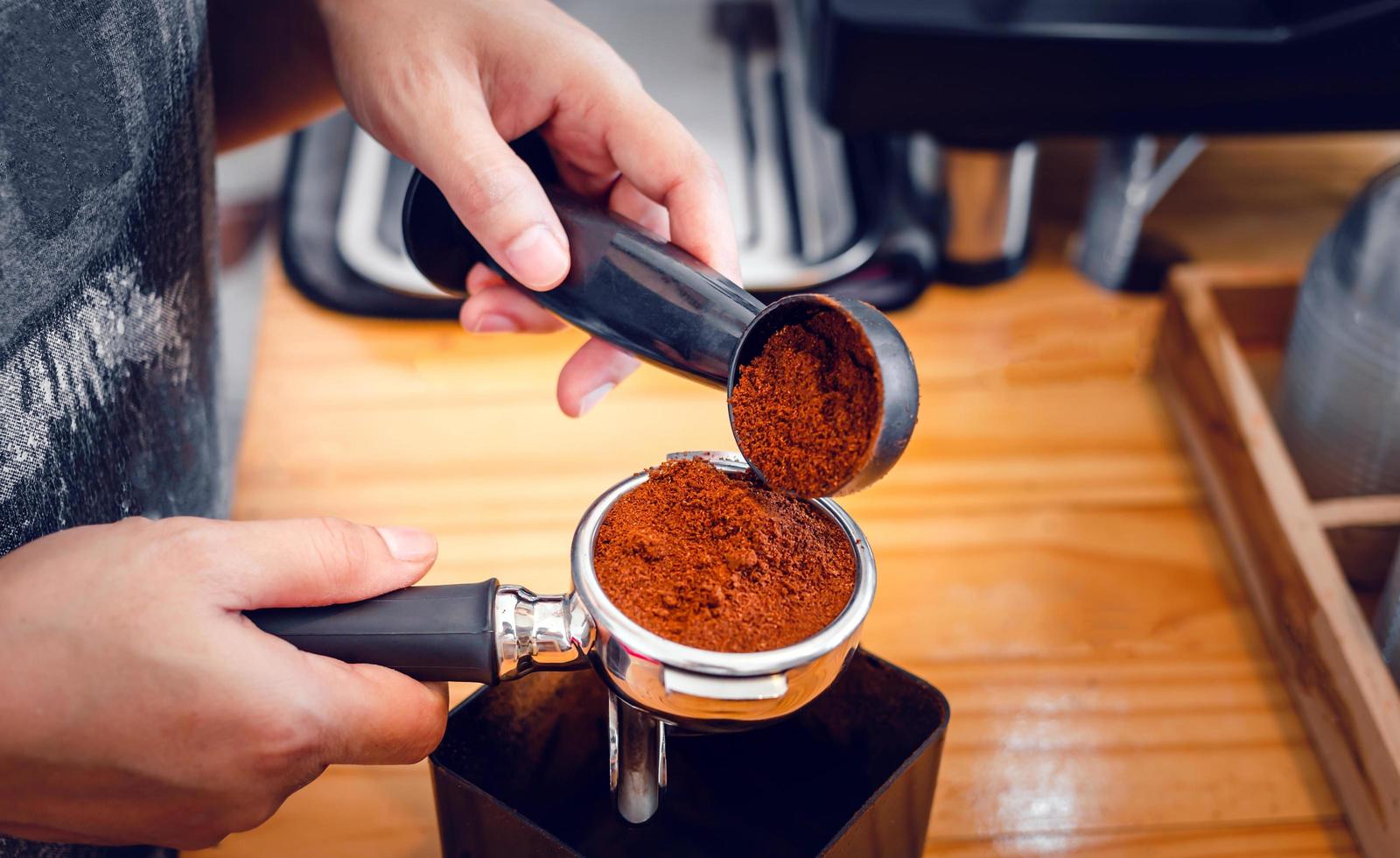 Barista pours coffee bean roaster powder ground coffee pouring into a portafilter with a barista hand at the coffee shop photo