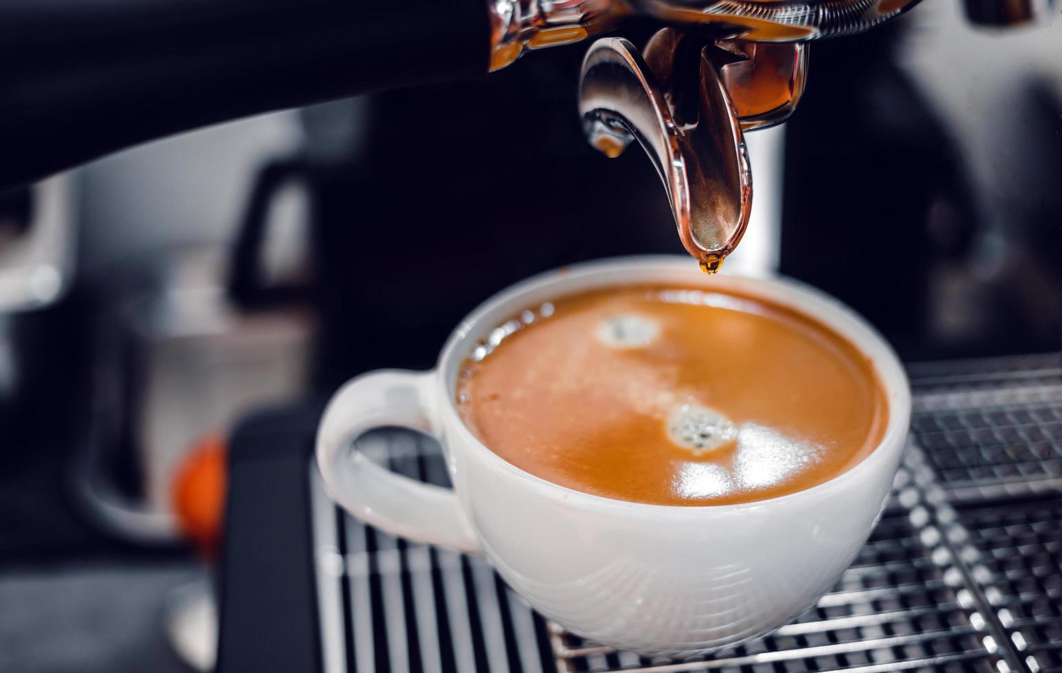 extracción de café de la máquina de café con un portafiltro que vierte café en una taza, espresso de la máquina de café en la cafetería foto