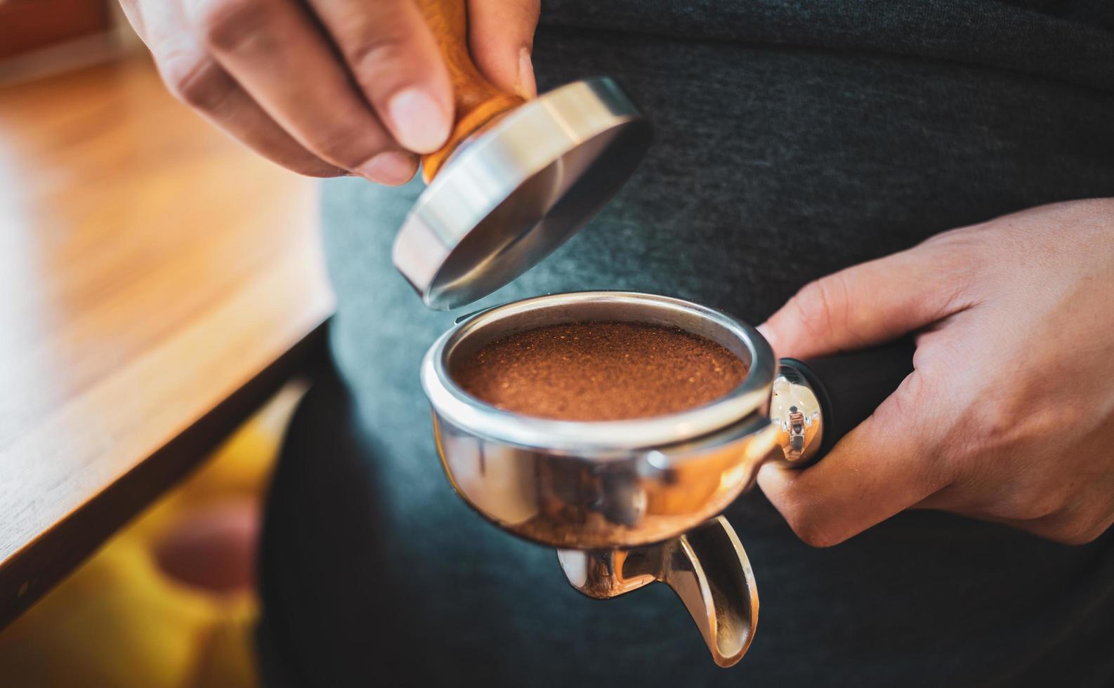 Close-up of hand Barista cafe making coffee with manual presses ground coffee using tamper at the coffee shop photo