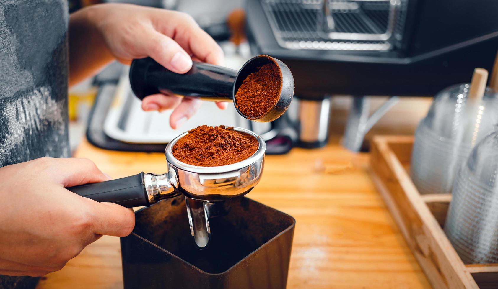 Barista pours coffee bean roaster powder ground coffee pouring into a portafilter with a barista hand at the coffee shop photo