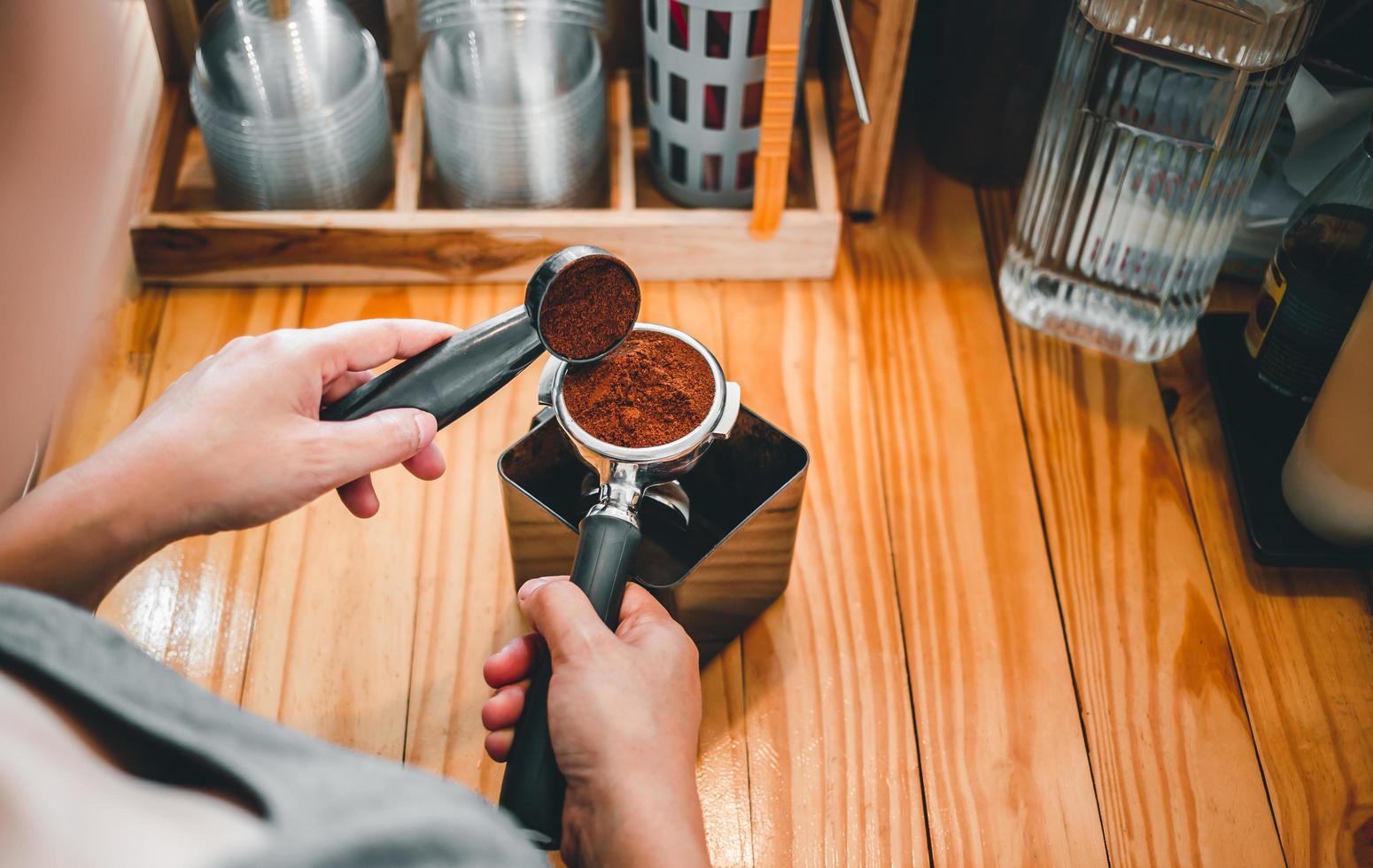 barista vierte café molido en polvo tostador de granos de café que se vierte en un portafiltro con una mano de barista en la cafetería foto