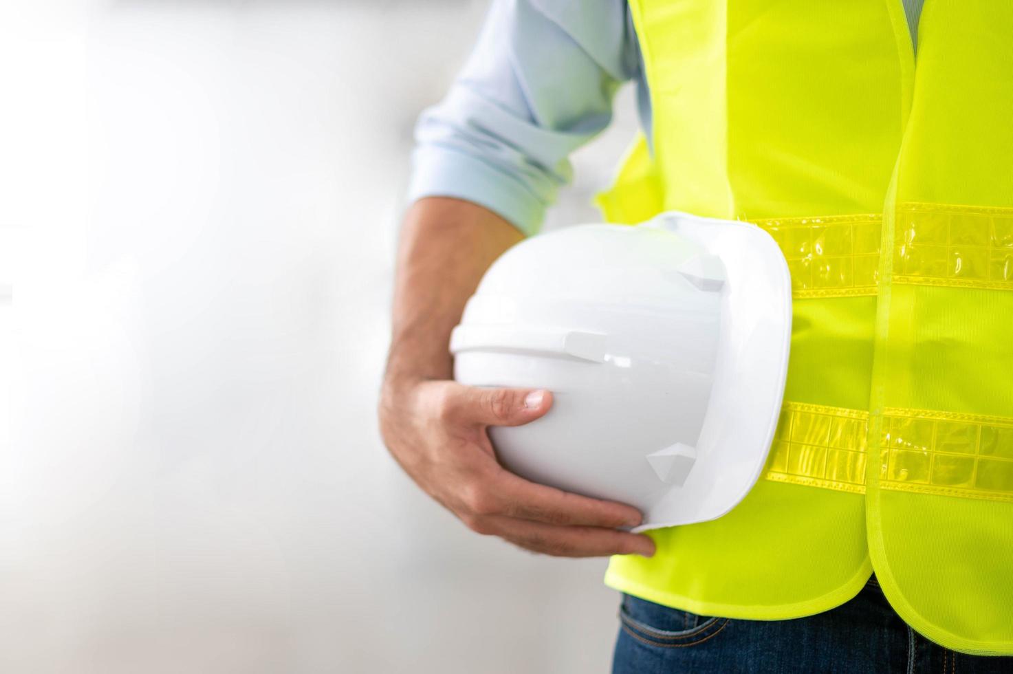 ingeniero sosteniendo casco con chaleco amarillo y listo para la seguridad laboral en el sitio. foto