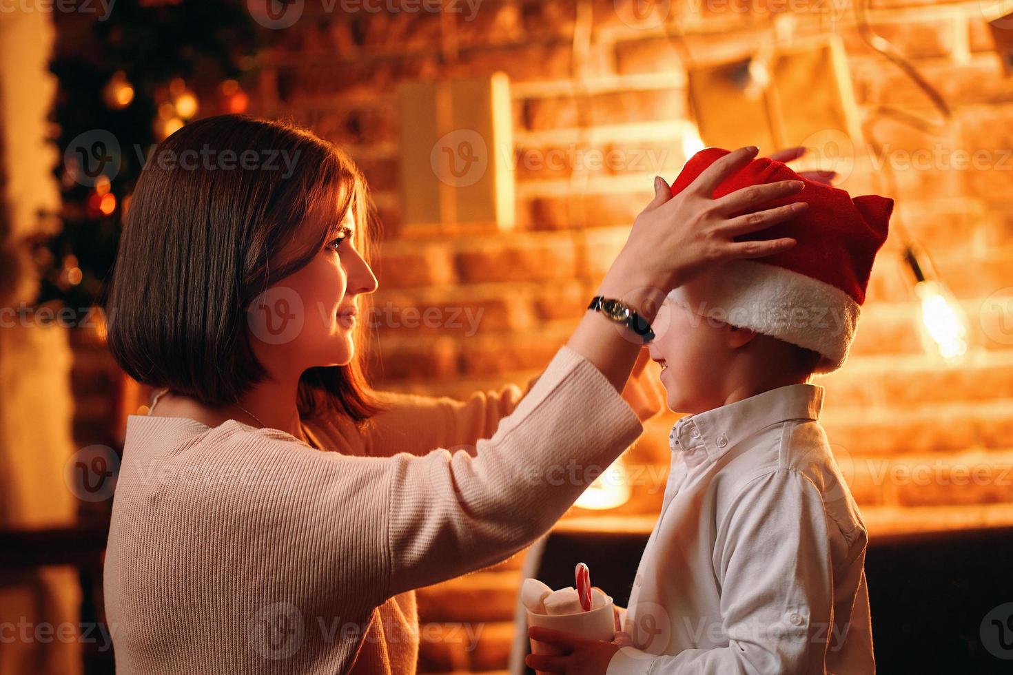 Mother puts Santa Claus Christmas hat on child. photo