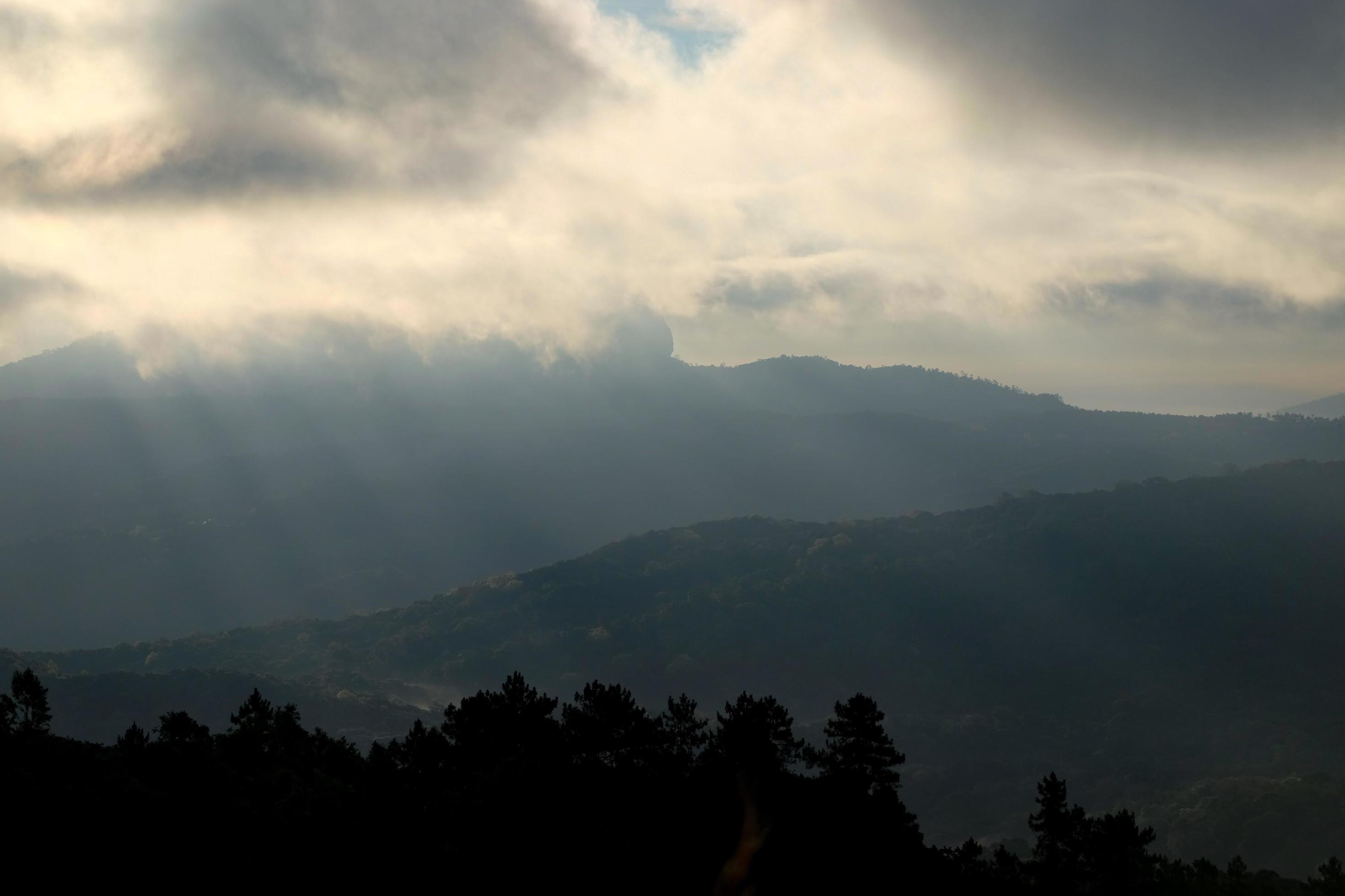 The sun shines through the clouds above the mountains 14947930 Stock