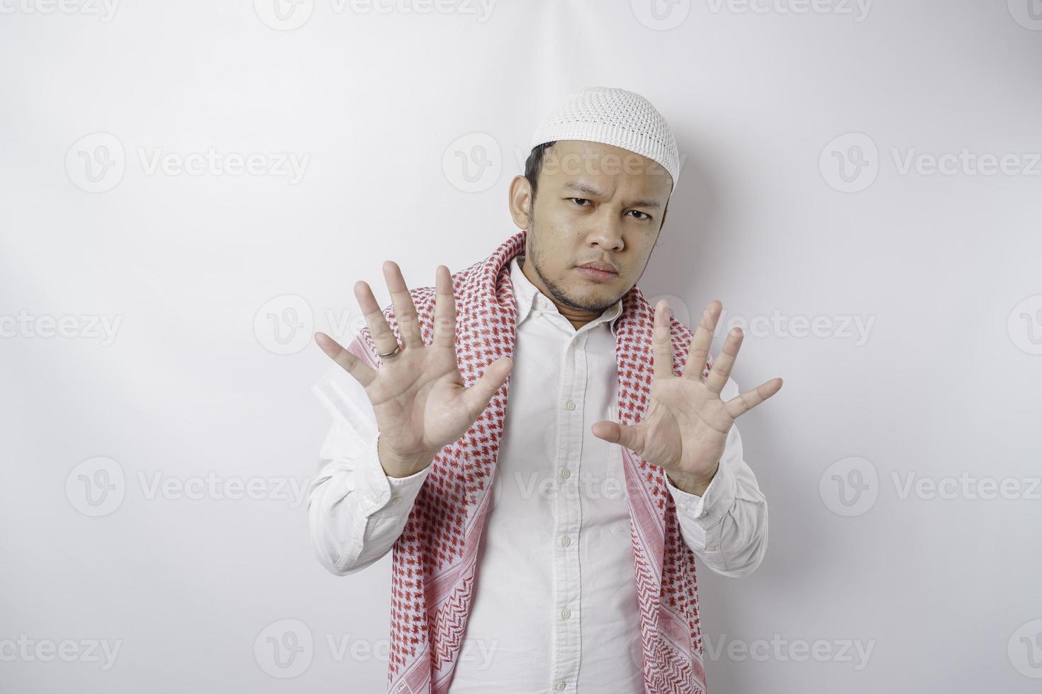 Young Asian Muslim man isolated on white background, looks depressed, face covered by fingers frightened and nervous. photo