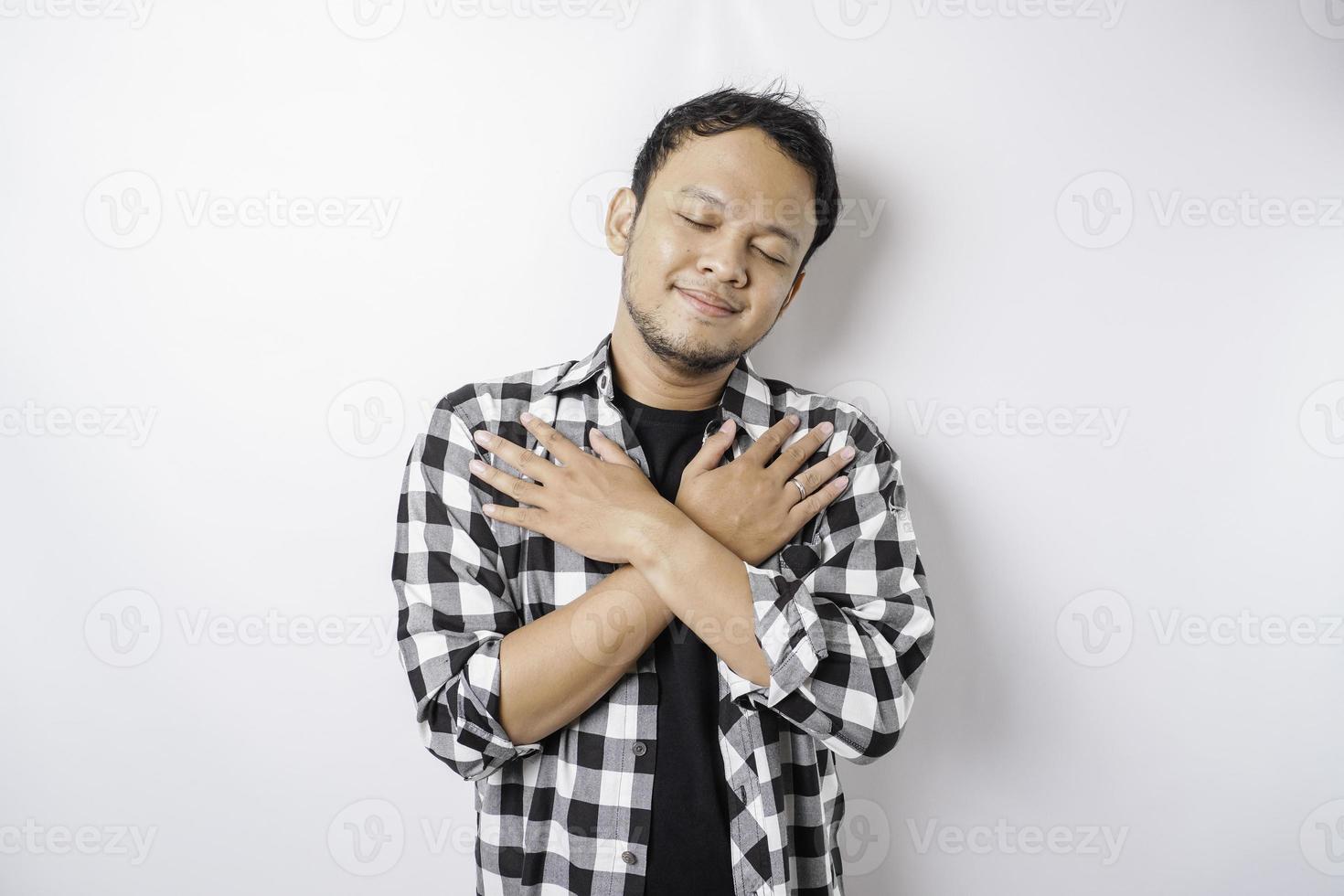 Portrait of a peaceful Asian man wearing tartan shirt is smiling and feel relief photo