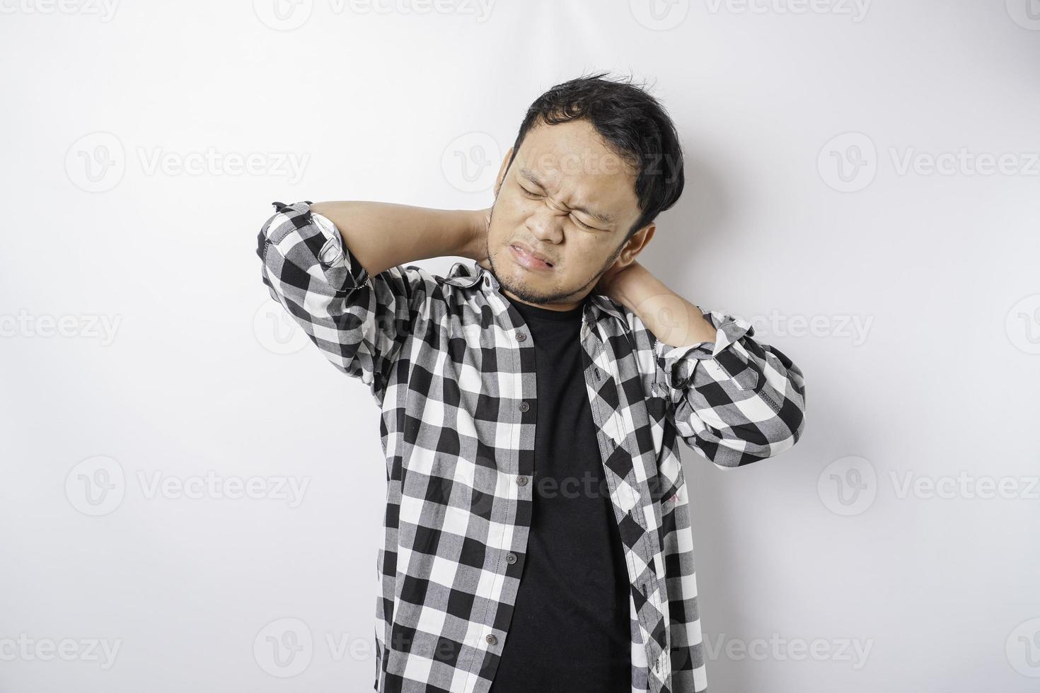 Tired upset young man suffering from pain, muscle spasm at workplace. Fatigue, deadline, pain and incorrect posture photo