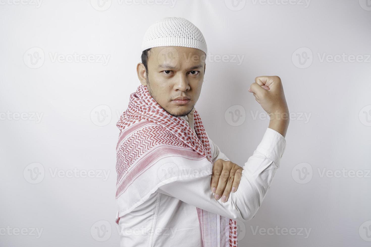 Excited Asian Muslim man showing strong gesture by lifting his arms and muscles smiling proudly photo