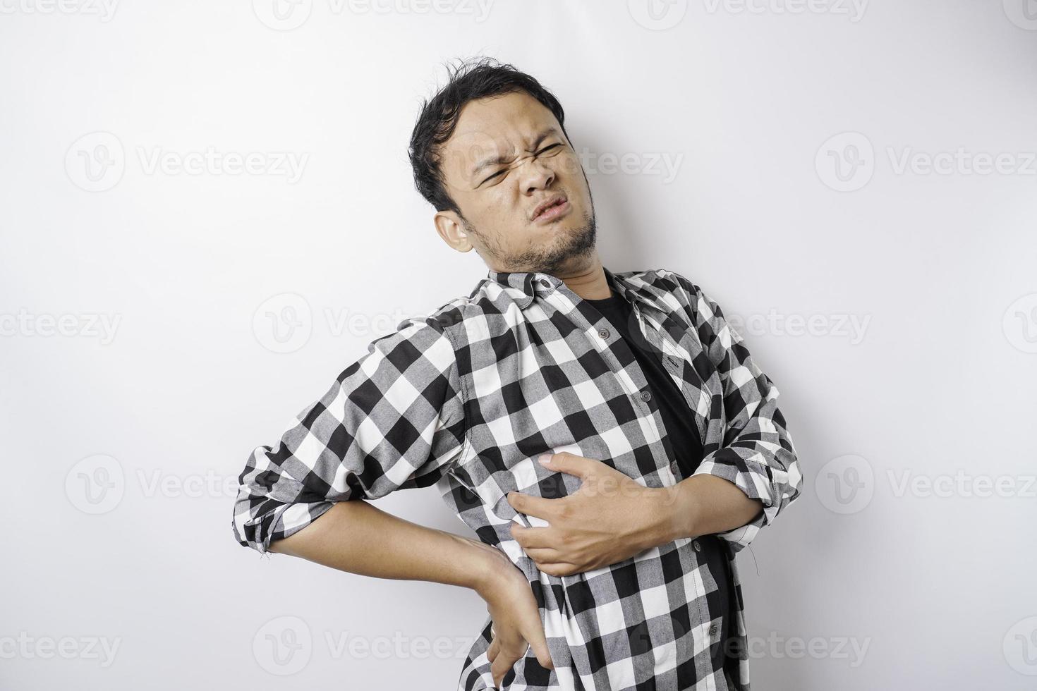 Tired upset young man suffering from back pain, muscle spasm at workplace. Fatigue, deadline, pain and incorrect posture photo