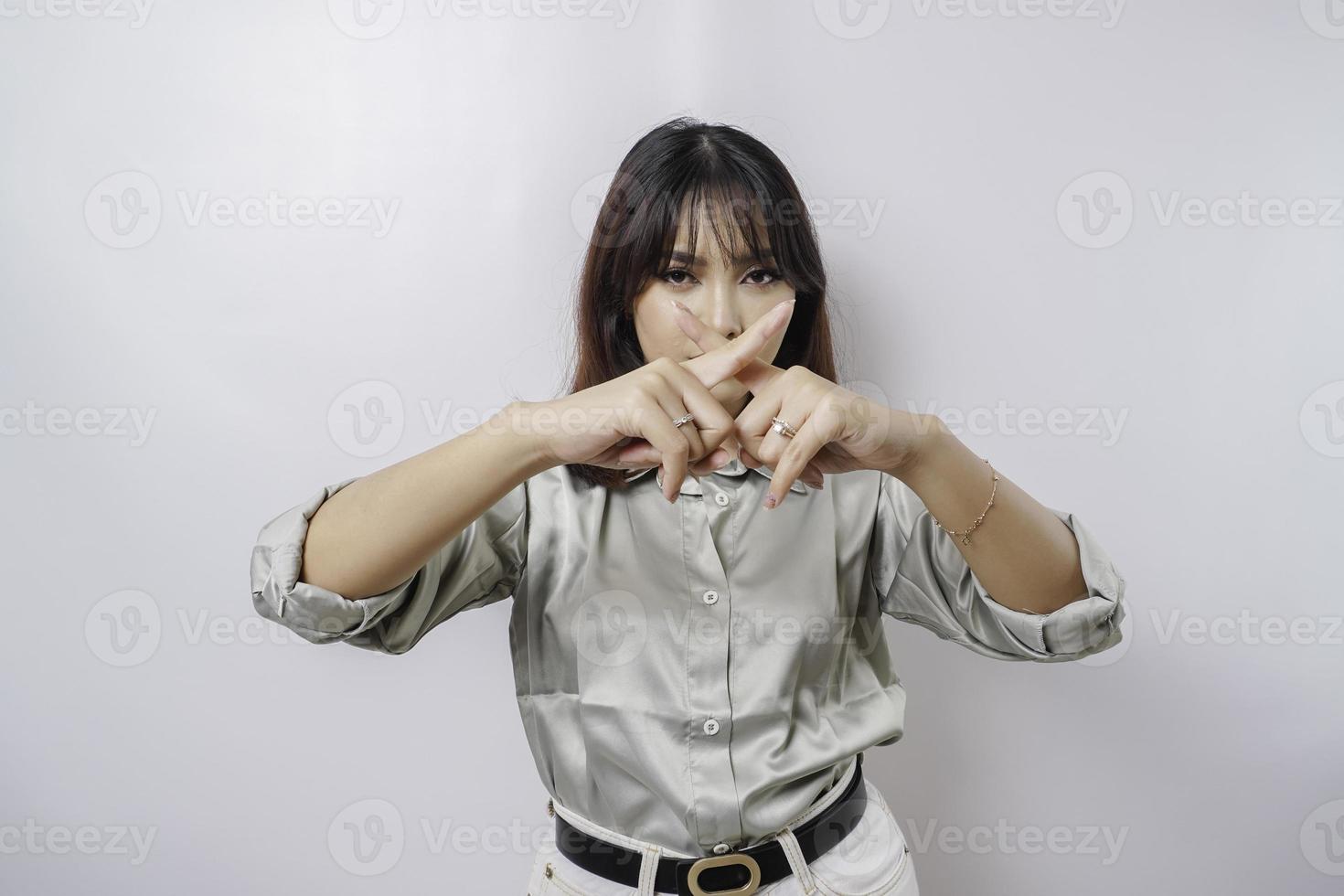 hermosa mujer asiática con camisa verde salvia con gesto de la mano plantea rechazo o prohibición con espacio de copia foto