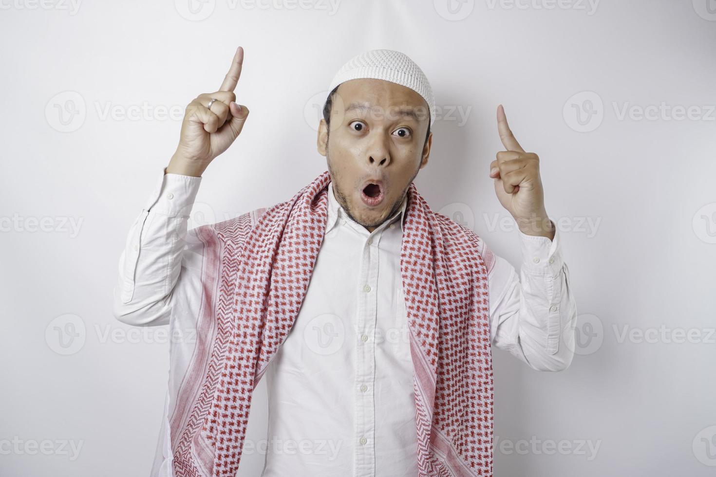 un musulmán asiático conmocionado señalando el espacio de la copia encima de él, aislado por un fondo blanco foto