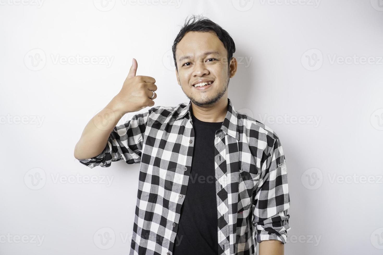 emocionado hombre asiático vestido con pantalones de tartán da pulgares hacia arriba gesto de aprobación, aislado por fondo blanco foto