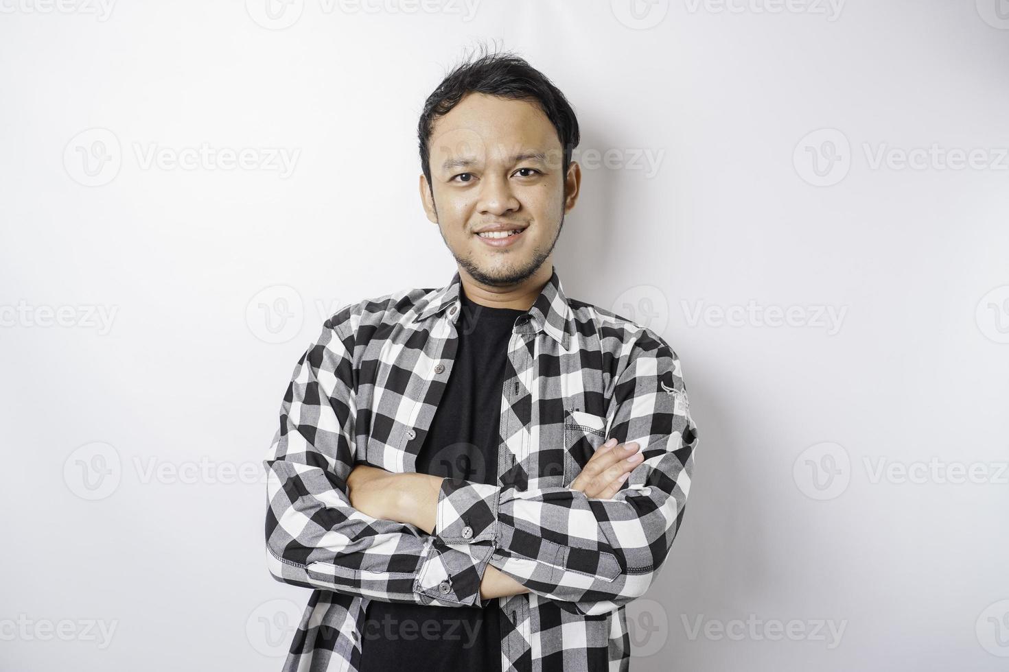 Portrait of a confident smiling Asian man wearing tartan shirt standing with arms folded and looking at the camera isolated over white background photo