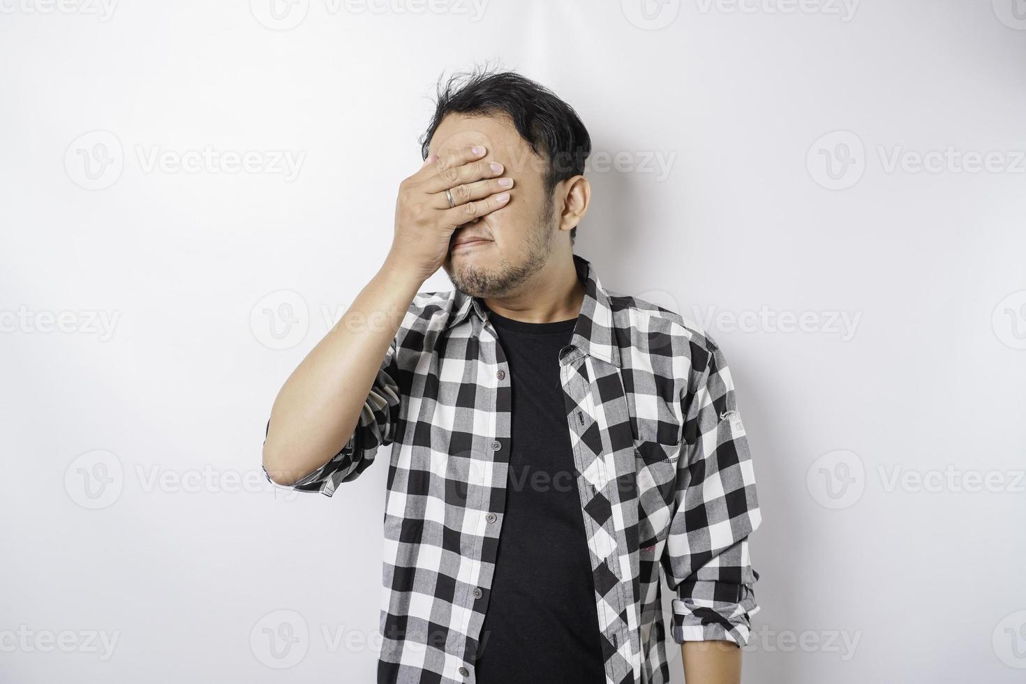 A portrait of a stressed Asian man wearing a tartan shirt isolated by white background looks depressed photo