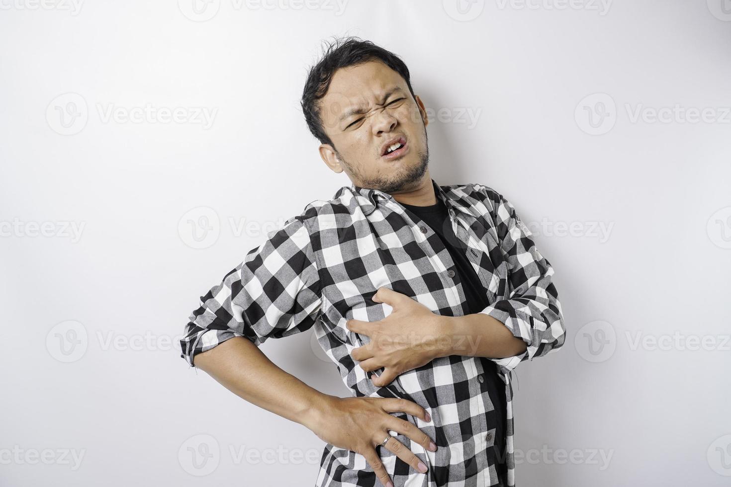 Tired upset young man suffering from back pain, muscle spasm at workplace. Fatigue, deadline, pain and incorrect posture photo
