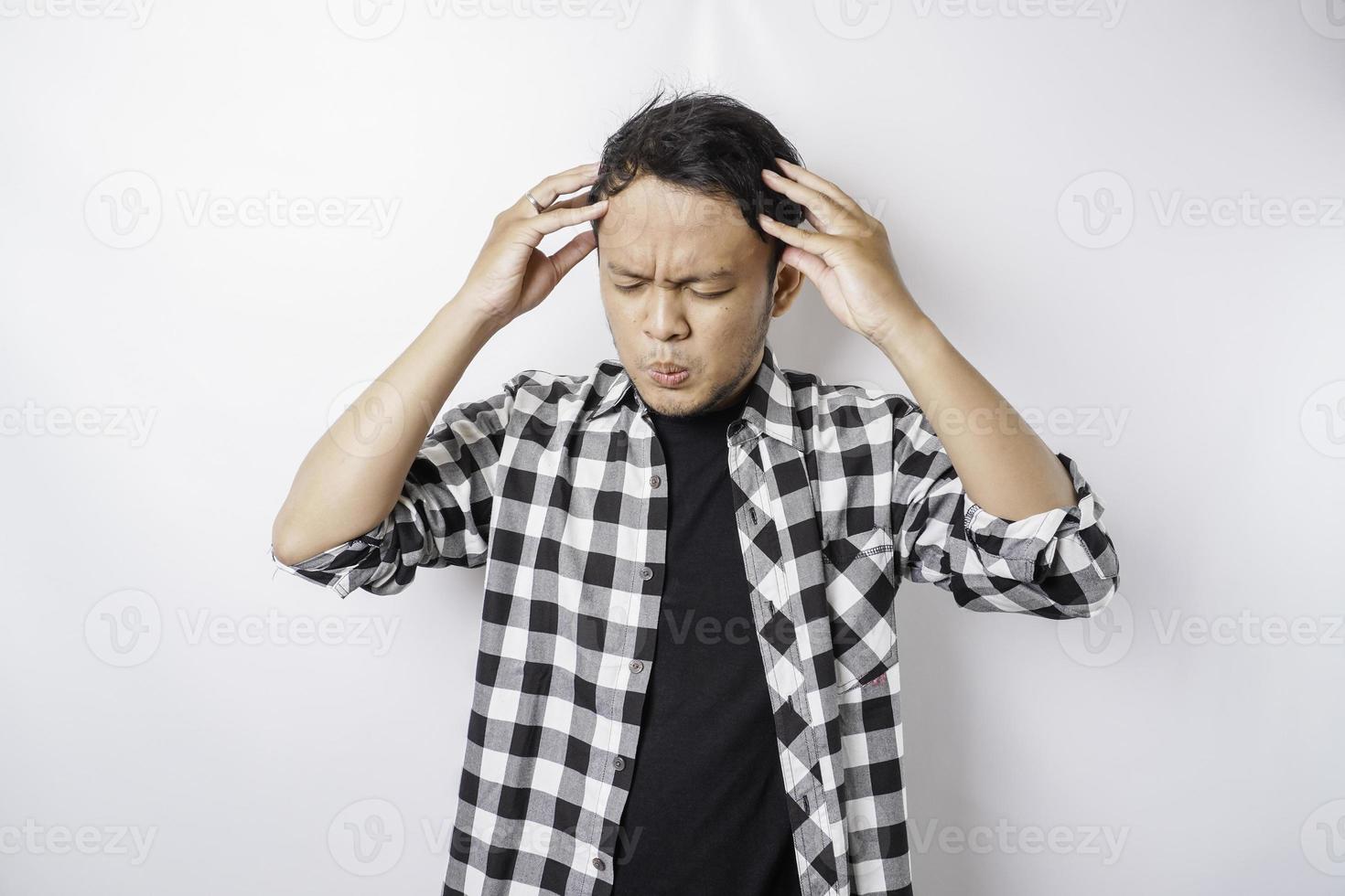 A portrait of a stressed Asian man wearing a tartan shirt isolated by white background looks depressed photo