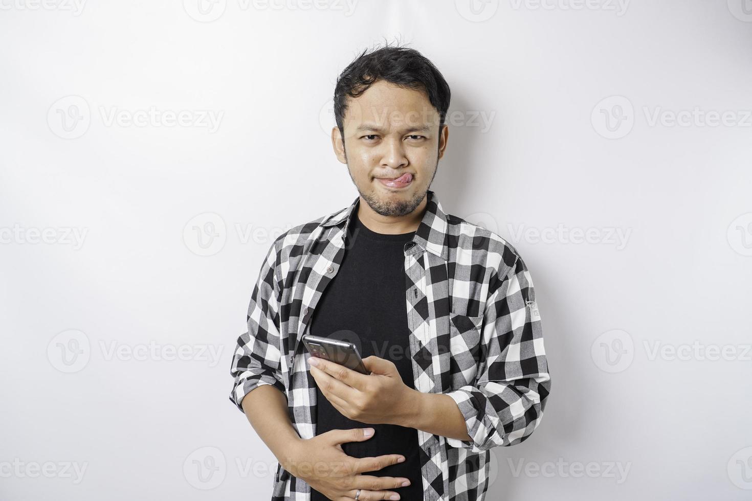 foto de un joven hambriento y emocionado sosteniendo su teléfono y preguntándose qué pedir comida deliciosa aislada en un fondo de color blanco