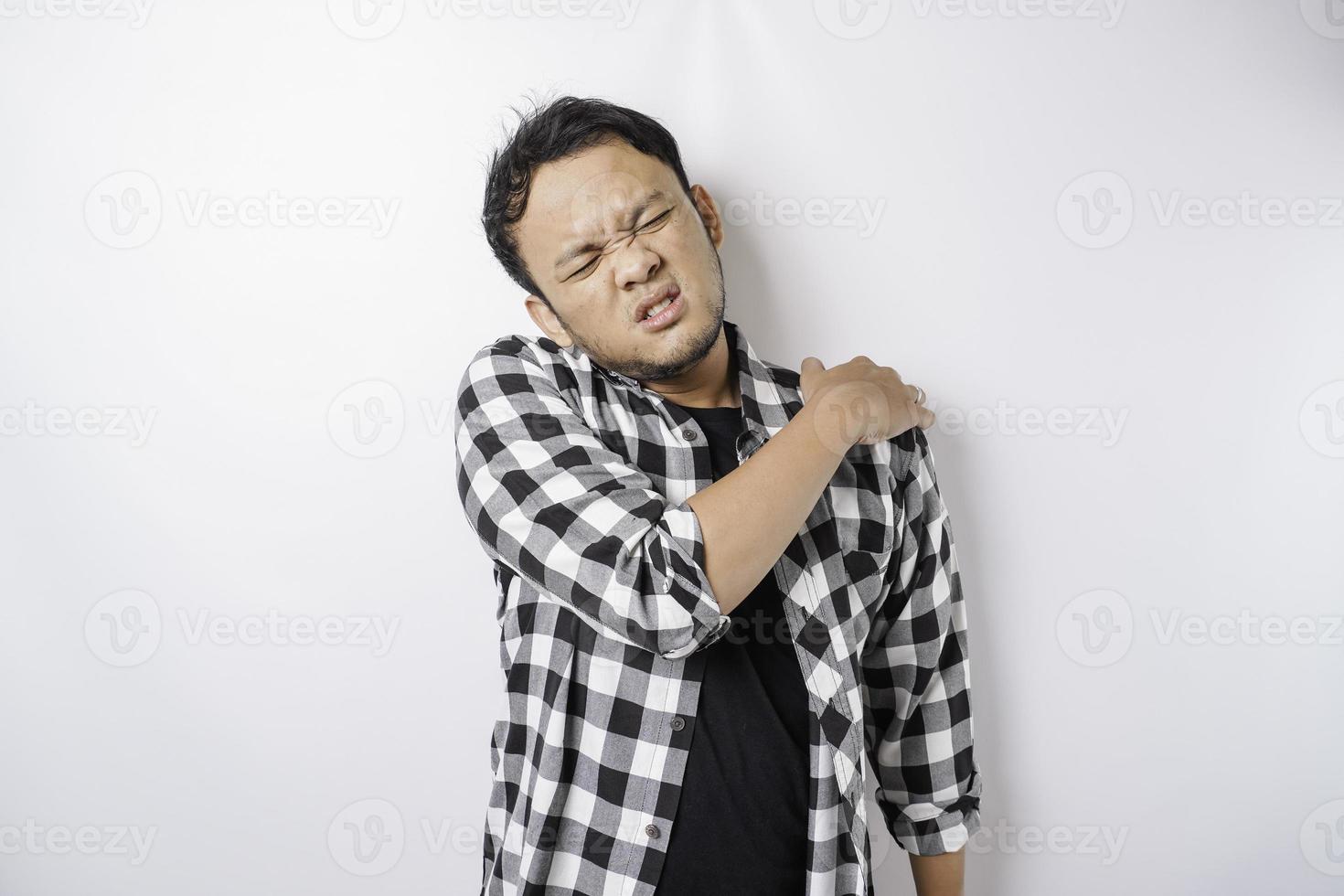 Tired upset young man suffering from pain, muscle spasm at workplace. Fatigue, deadline, pain and incorrect posture photo