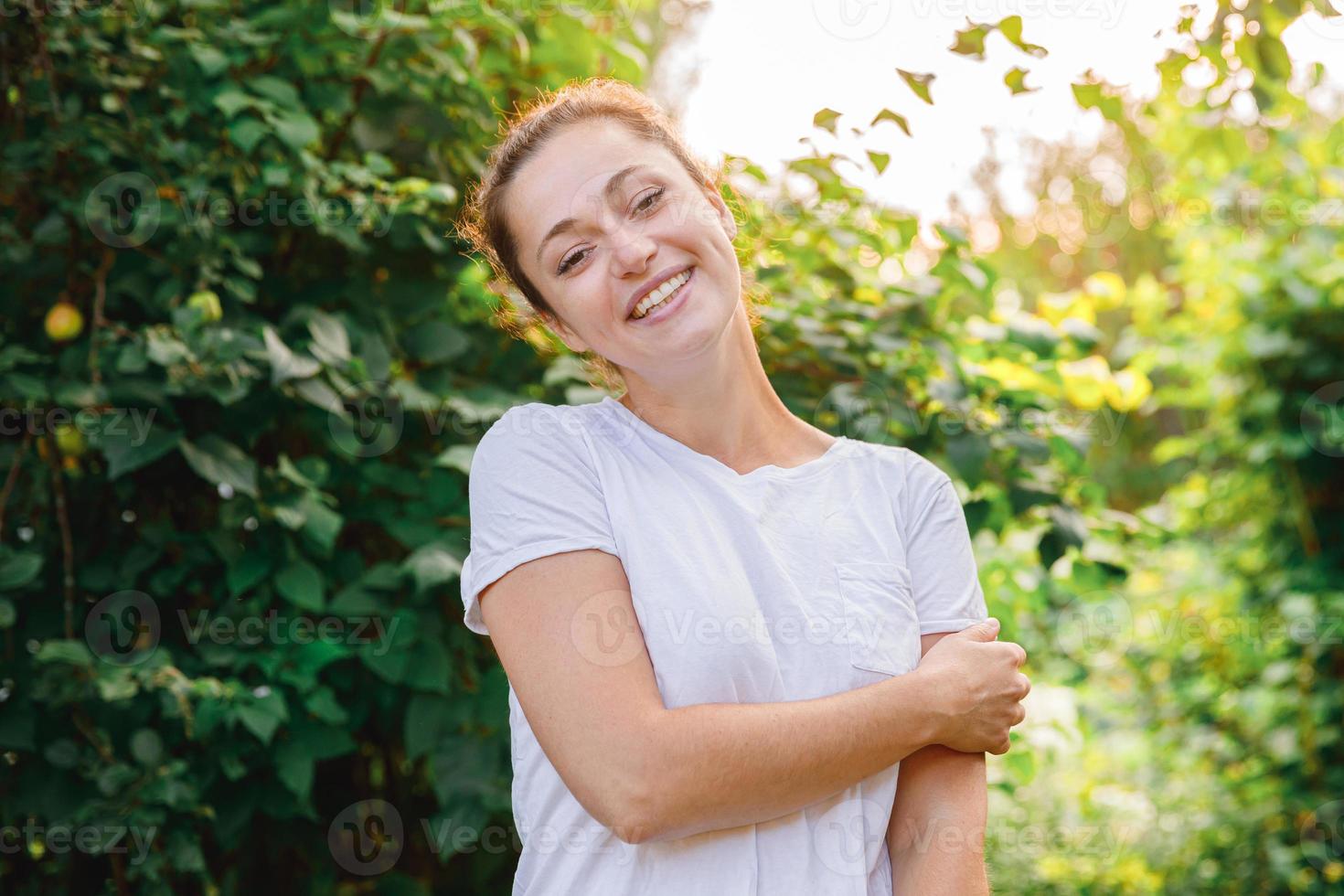 Young woman smiling outdoor. Beautiful brunete girl resting on park or garden green background. Free happy woman at summertime. Freedom happiness carefree happy people concept. photo