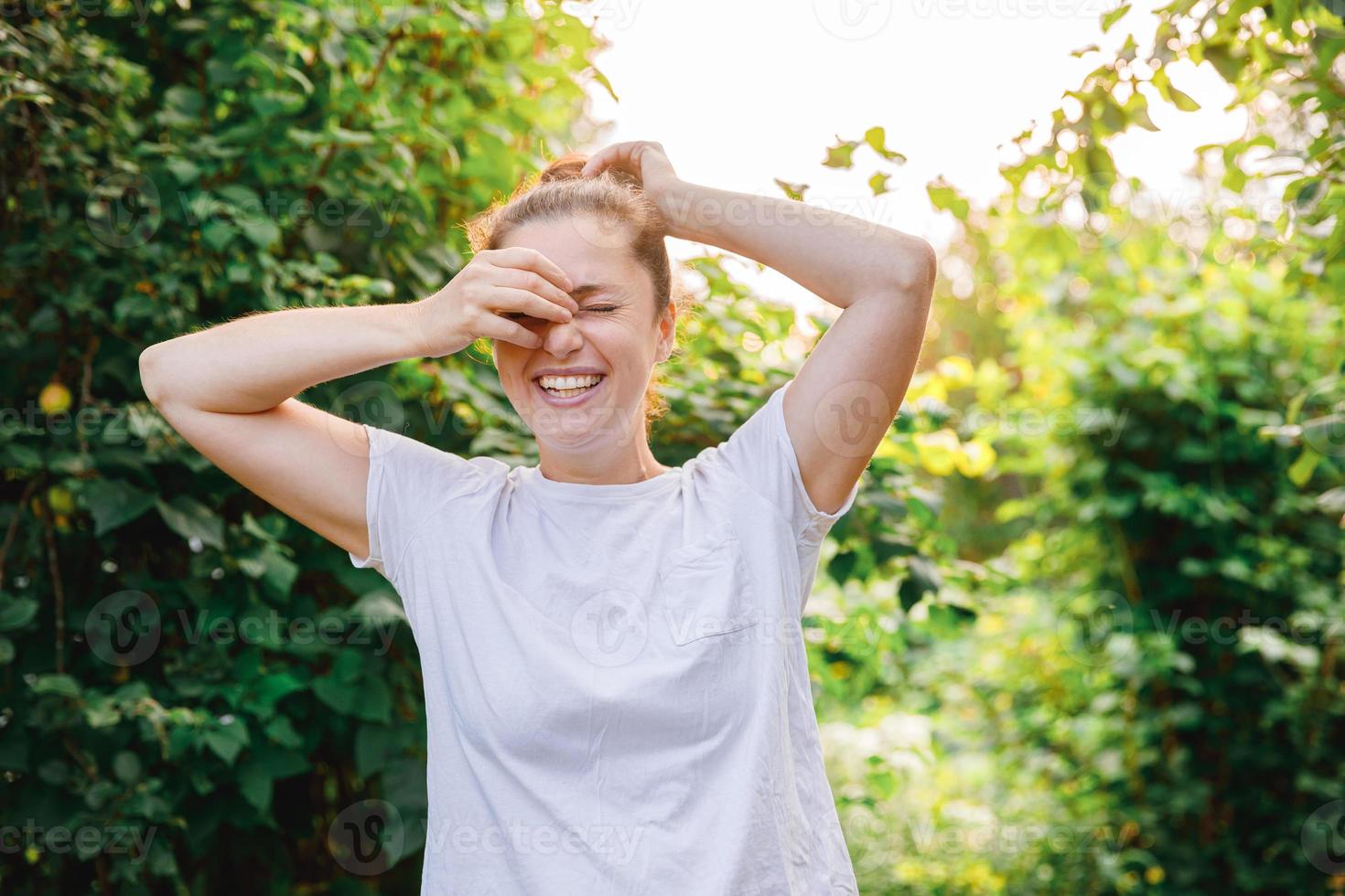 mujer joven sonriendo al aire libre. hermosa chica brunete descansando sobre un fondo verde de parque o jardín. mujer feliz libre en verano. libertad felicidad despreocupada gente feliz concepto. foto