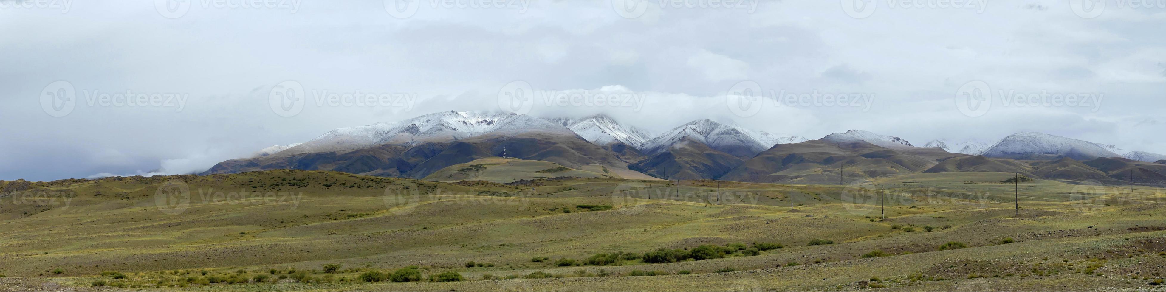 Clouds lying on the tops of snow-capped mountains in the Altai mountains photo