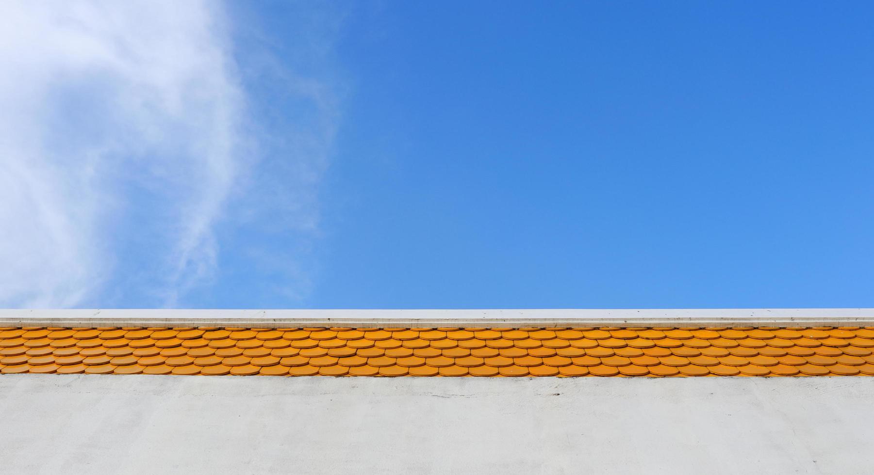 Bright orange color rooftop of building and bright blue sky with cloud. photo