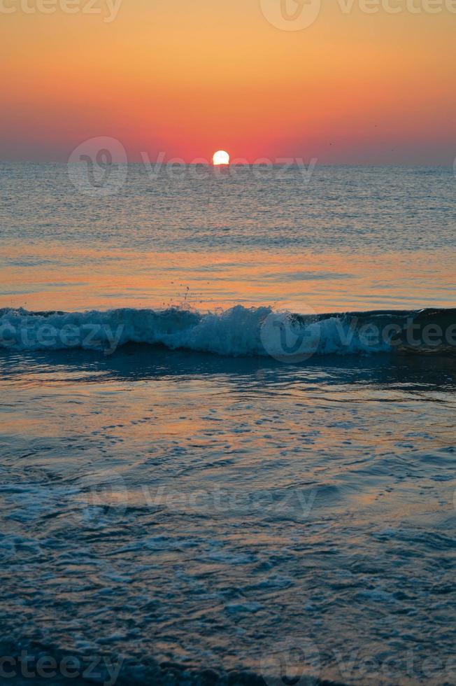 hermosa puesta de sol de verano en la playa, olas y arena foto