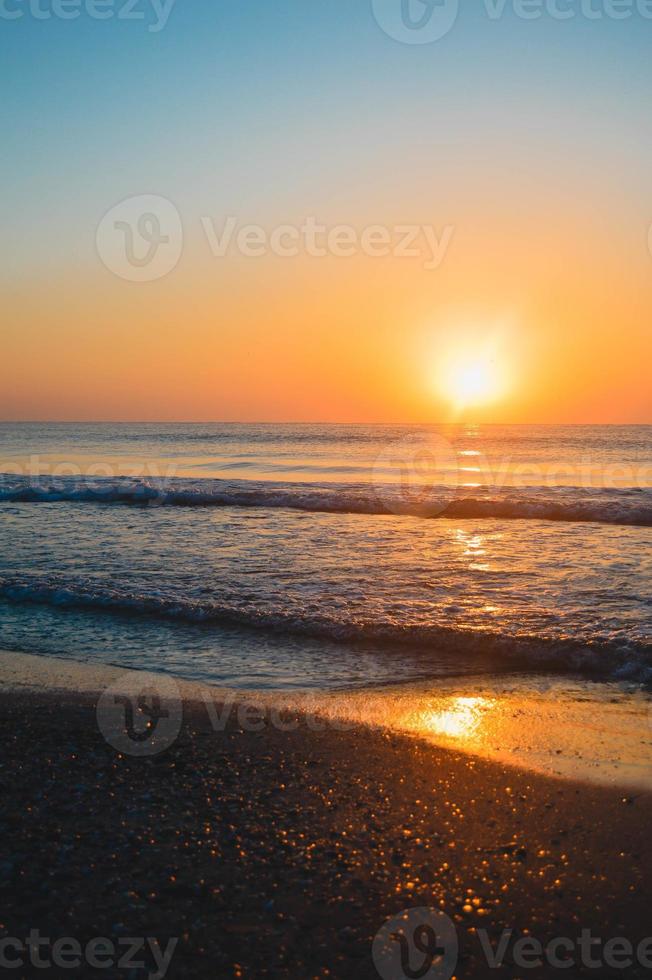 Beautiful summer sunset at the beach, waves and sand photo