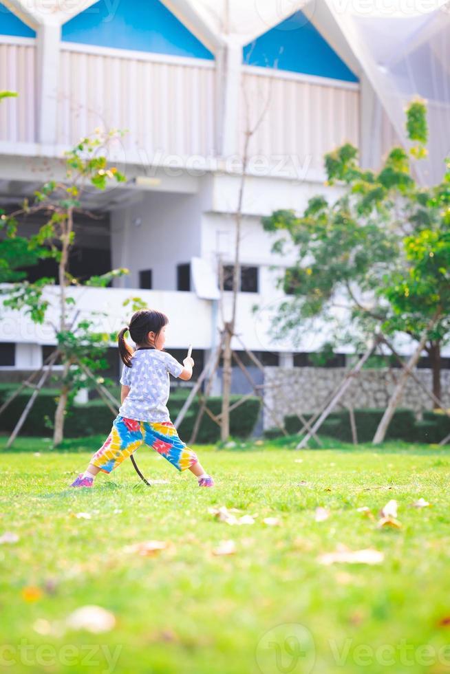 niña de retrato haciendo ejercicio sobre hierba verde en verano o primavera. niño feliz jugando con la naturaleza. niños de 4 años. imagen vertical espacio vacio. vista trasera trasera. foto