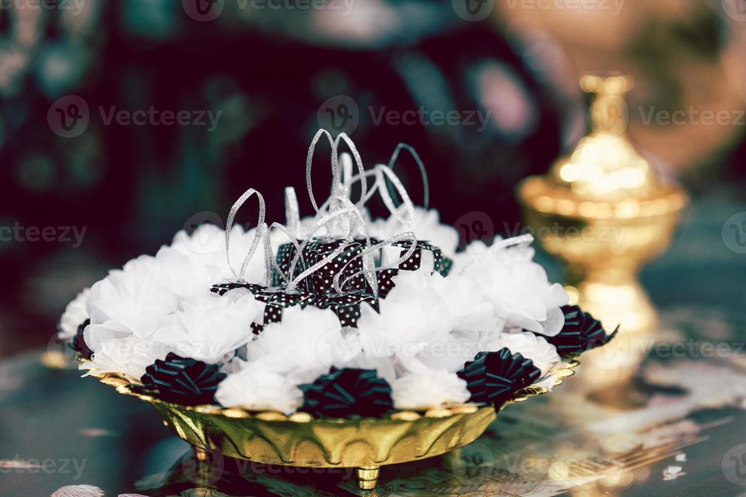 las medallas para el altar estaban envueltas en papel de morera blanco y negro y cintas, bellamente dispuestas en una bandeja de color amarillo dorado. espalda borrosa para grava. espacio vacío para ingresar texto. foto