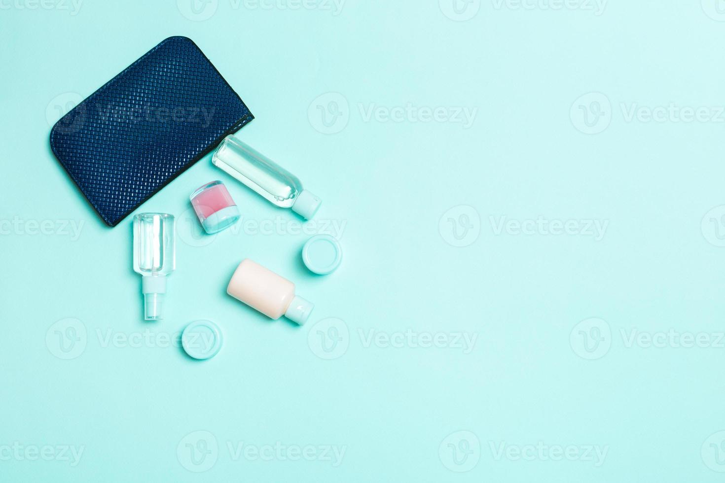 bolso cosmético de mujer con un conjunto de productos de belleza y crema para el cuidado del cuerpo sobre fondo azul pastel con espacio de copia para su diseño foto