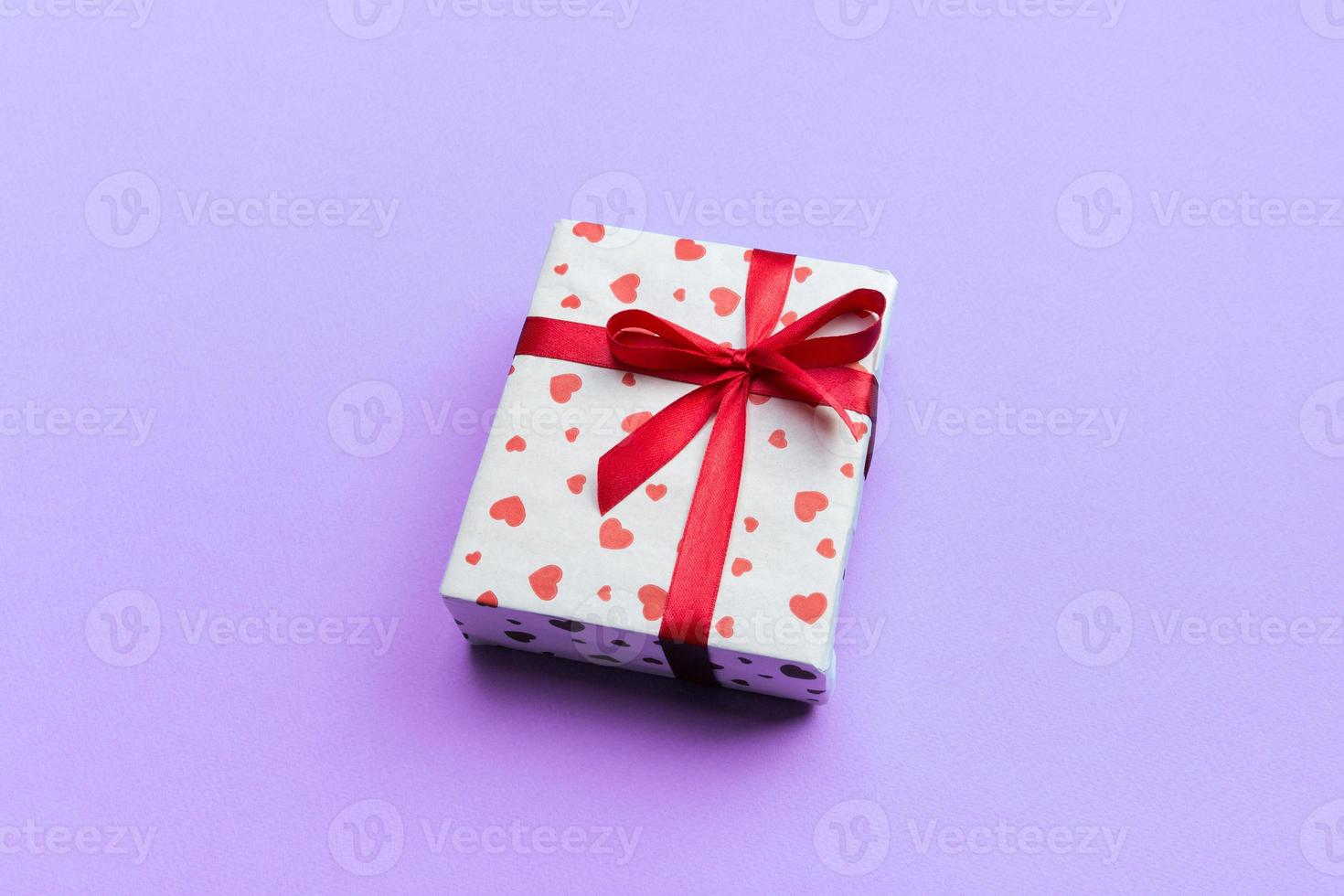Background with gift box and hearts on purple Background. Top view with copy space for text photo