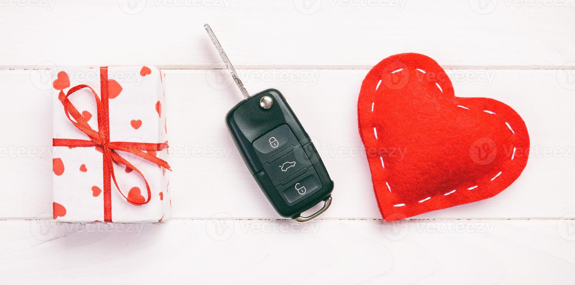 Valentine or other holiday handmade present in paper with red hearts, car keys and gifts box in holiday wrapper. box gift on white wooden table top view with copy space, empty space for design photo