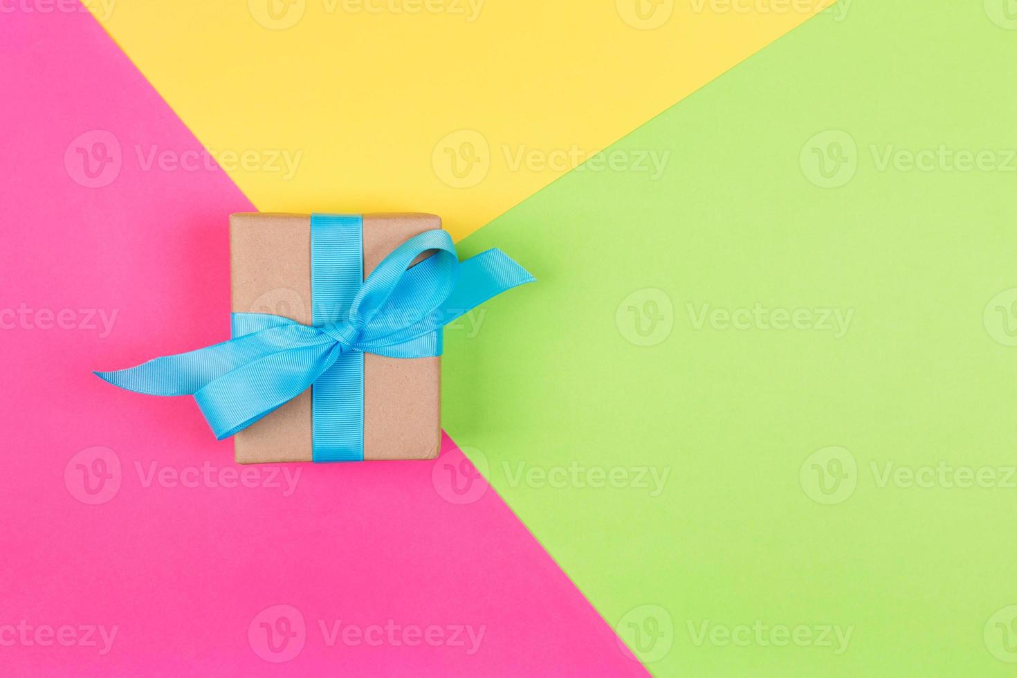 gift wrapped and decorated with blue bow on colored background with copy space. Flat lay, top view photo