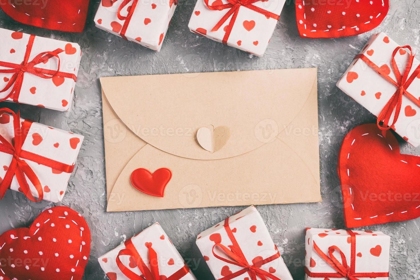 correo de sobre con corazón rojo y caja de regalo sobre fondo de cemento gris. tarjeta de san valentín, amor o concepto de saludo de boda foto