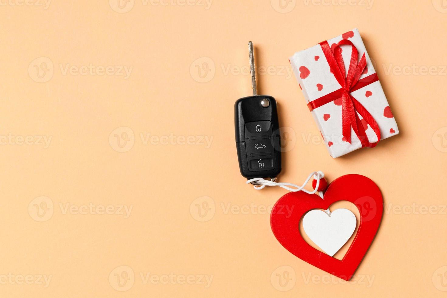 Top view of gift box, car key and wooden heart on colorful background. Luxury present for Valentine's day photo