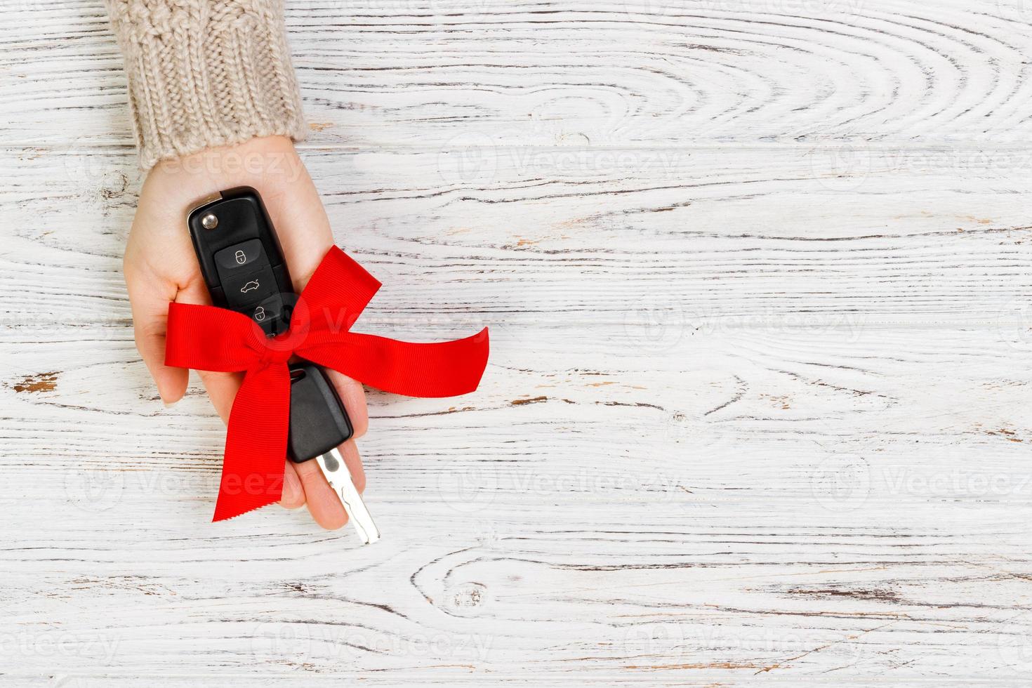 Woman hand hold car key with red bow. Giving a car as a gift photo