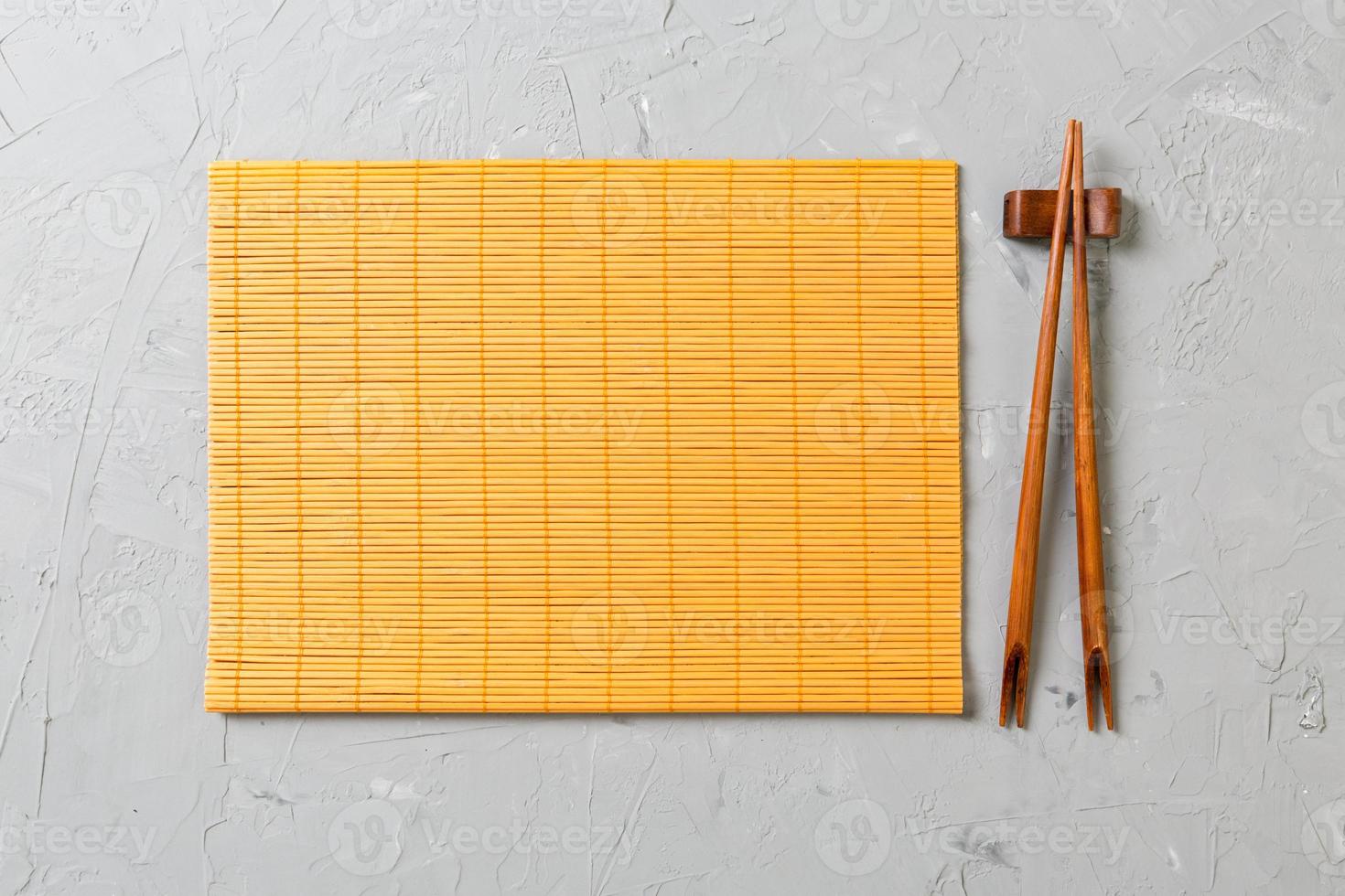 two sushi chopsticks with empty bamboo mat or wood plate on stone Background Top view with copy stace photo