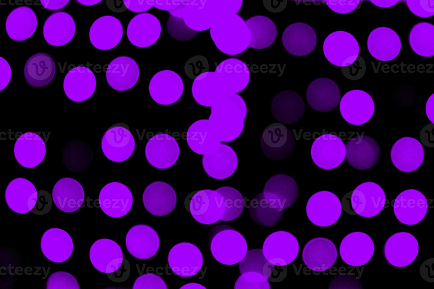 Unfocused abstract purple bokeh on black background. defocused and blurred many round light photo