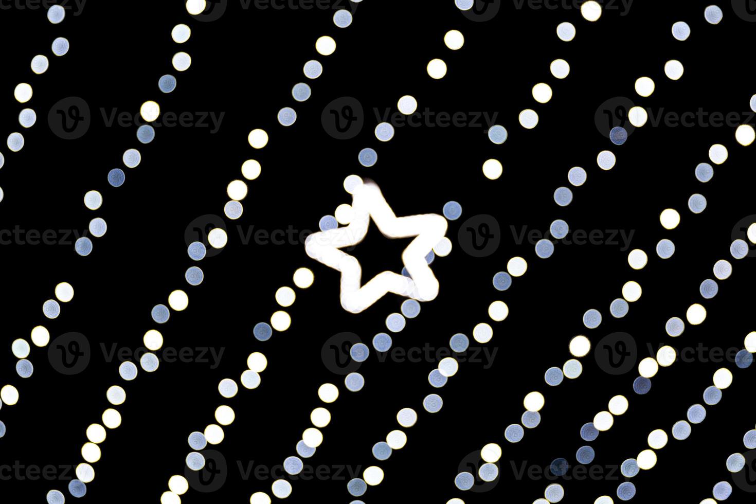 Unfocused abstract white bokeh with star of light on black background. defocused and blurred many round light photo